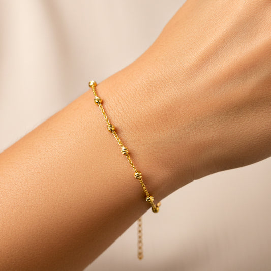 Mano de mujer usando una pulsera con esferas facetadas en oro amarillo de 18 quilates de Joyería Caracas. 