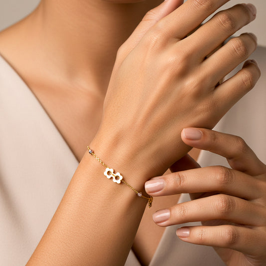 Mano de mujer usando una pulsera de flores y esferas facetada en oro amarillo, blanco y rosa de 18 quilates de Joyería Caracas. 