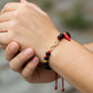 Mano de modelo usando una pulsera tejida de azabaches en hilo color negro con 2 esferas facetadas y herraje con forma de infinito en oro amarillo de 18 quilates de Joyería Caracas. 