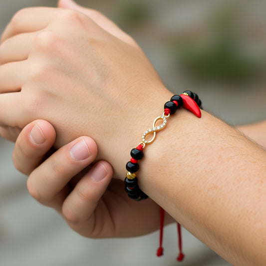 Mano de modelo usando una pulsera tejida de azabaches en hilo color negro con 2 esferas facetadas y herraje con forma de infinito en oro amarillo de 18 quilates de Joyería Caracas. 