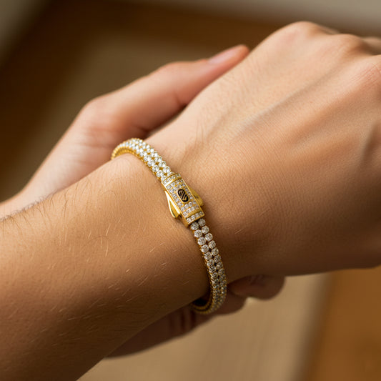 Mano de mujer usando una pulsera Mónaco en oro amarillo de 18 quilates con cristales de color blanco de Joyería Caracas. 