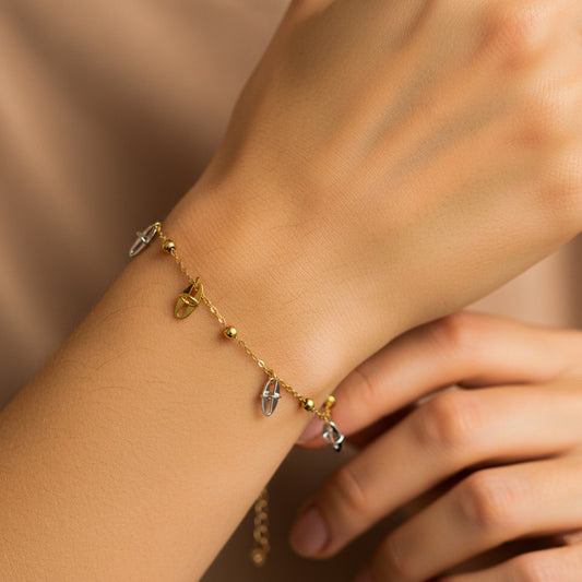Mano de mujer usando una pulsera con formas de óvalos en oro amarillo y blanco de 18 quilates de Joyería Caracas. 