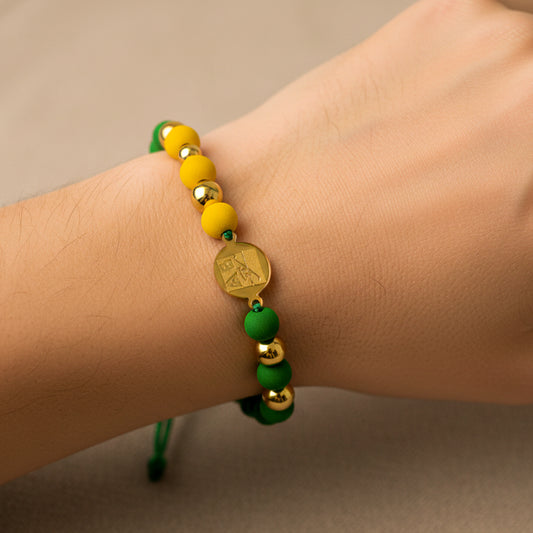 Mano de mujer usando una pulsera tejida personalizada con temática del Atlético Bucaramanga con placa grabada del AB en oro amarillo de 18 quilates de Joyería Caracas. 