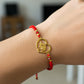 Mano de modelo usando una pulsera tejida en hilo color rojo con dije de unicornio en oro amarillo de 18 quilates con bisutería de calidad de Joyería Caracas. 