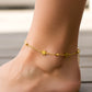 Tobillo de mujer usando una tobillera con estrellas y esferas en oro amarillo de 18 quilates de Joyería Caracas. 