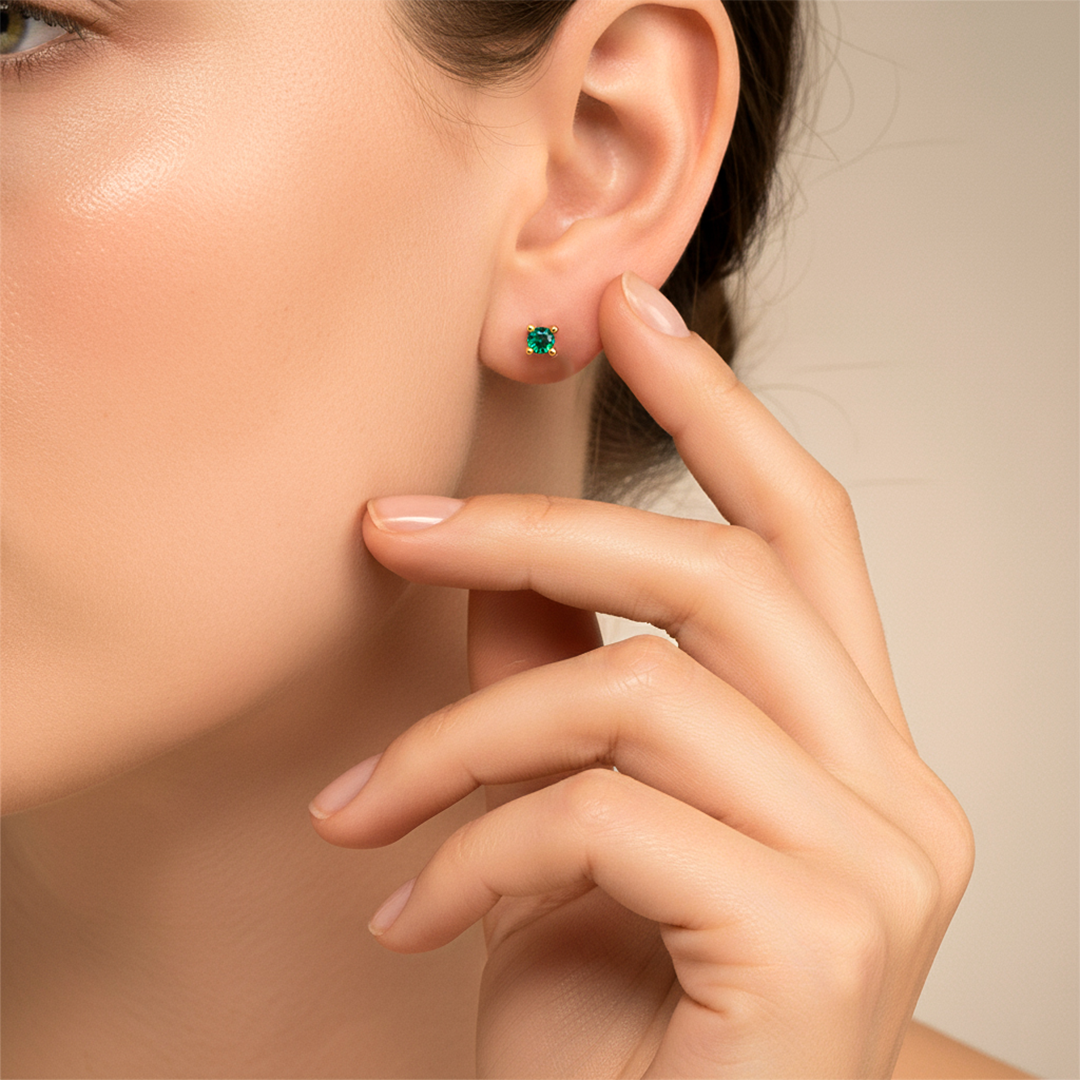 Oreja de modelo usando un topito en oro amarillo de 18 quilates con Esmeralda redonda de Joyería Caracas. 