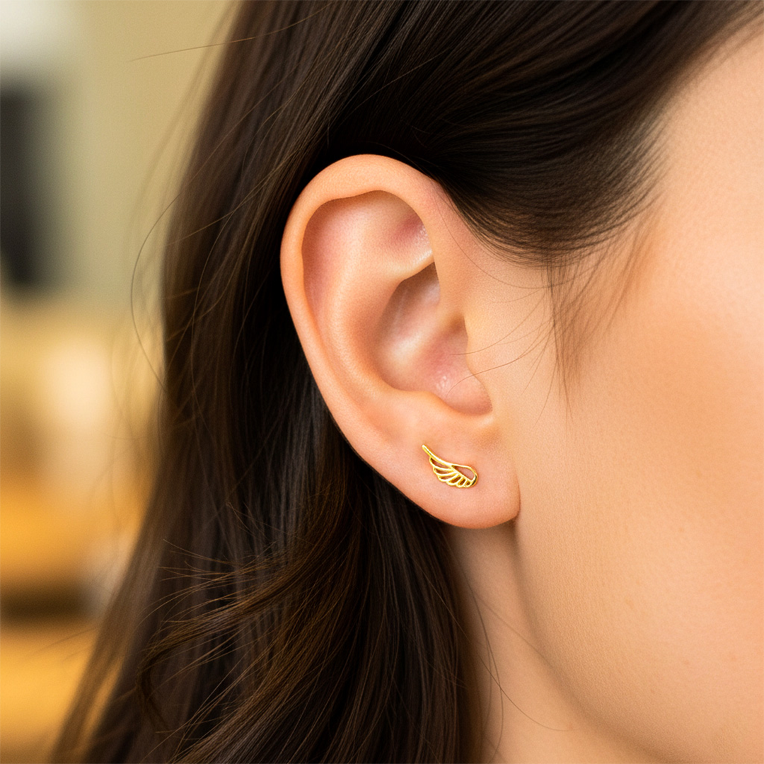 Oreja de modelo usando un topito en forma de ala en oro amarillo de 18 quilates de Joyería Caracas. 