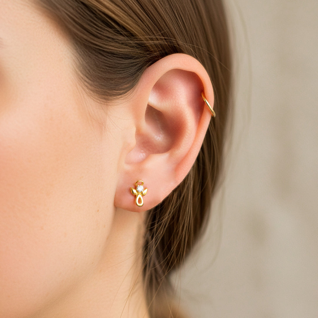 Oreja de modelo usando un topito en forma de ángel en oro amarillo de 18 quilates con cristal de color blanco de Joyería Caracas. 