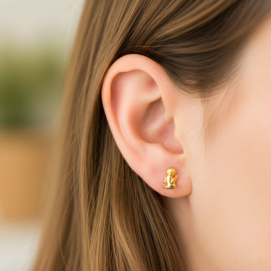 Oreja de modelo usando un topito en forma de ángel rezando en oro amarillo de 18 quilates de Joyería Caracas. 