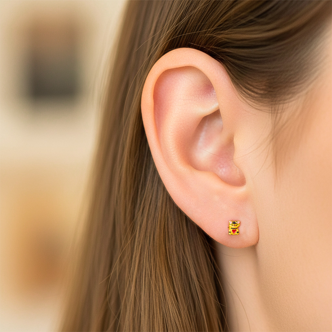 Oreja de modelo usando un topito en forma de gato en oro amarillo de 18 quilates de Joyería Caracas. 