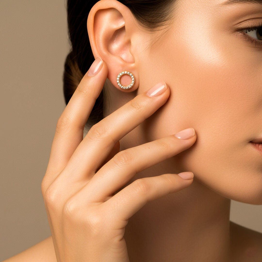 Oreja de modelo usando un topito en forma de círculo en oro amarillo de 18 quilates en oro amarillo de 18 quilates con cristales de color blanco de Joyería Caracas. 