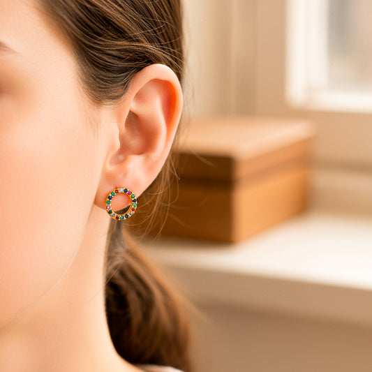 Oreja de modelo usando un topito circular en oro amarillo de 18 quilates con cristales de distintos colores de Joyería Caracas. 