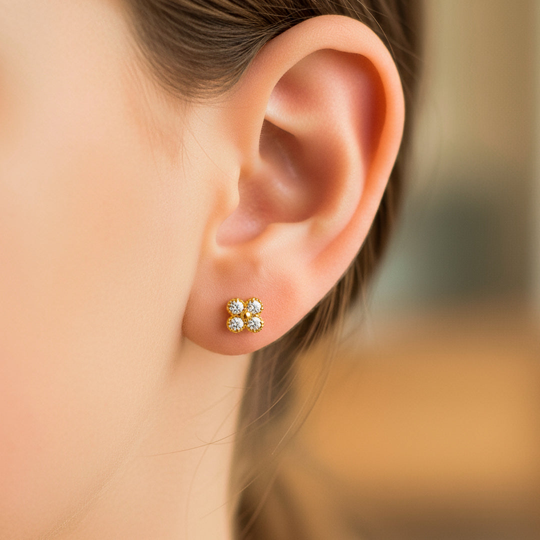 Oreja de modelo usando un topito en forma de trébol en oro amarillo de 18 quilates con cristales de color blanco de Joyería Caracas. 