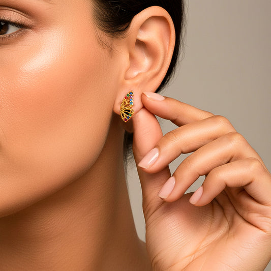 Oreja de modelo usando un topito en forma de ala de mariposa en oro amarillo de 18 quilates con cristales de distintos colores de Joyería Caracas. 