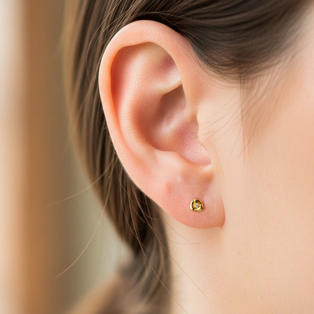 Oreja de modelo usando un topito en forma de corazón en 3 partes en oro amarillo de 18 quilates con cristal en el centro de Joyería Caracas. 