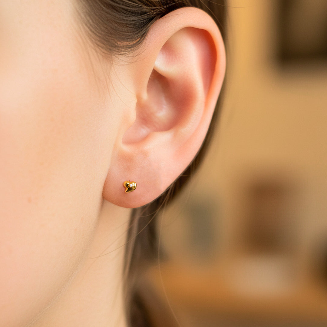 Oreja de modelo usando un topito en forma de corazón en oro amarillo de 18 quilates con cristal de Joyería Caracas. 