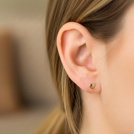 Oreja de modelo usando un topito en forma de corazón calado en oro amarillo de 18 quilates con cristales de color blanco de Joyería Caracas. 