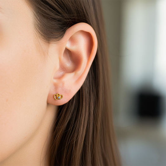 Oreja de modelo usando un topito en forma de corazones enlazados en oro amarillo de 18 quilates con cristal de Joyería Caracas. 