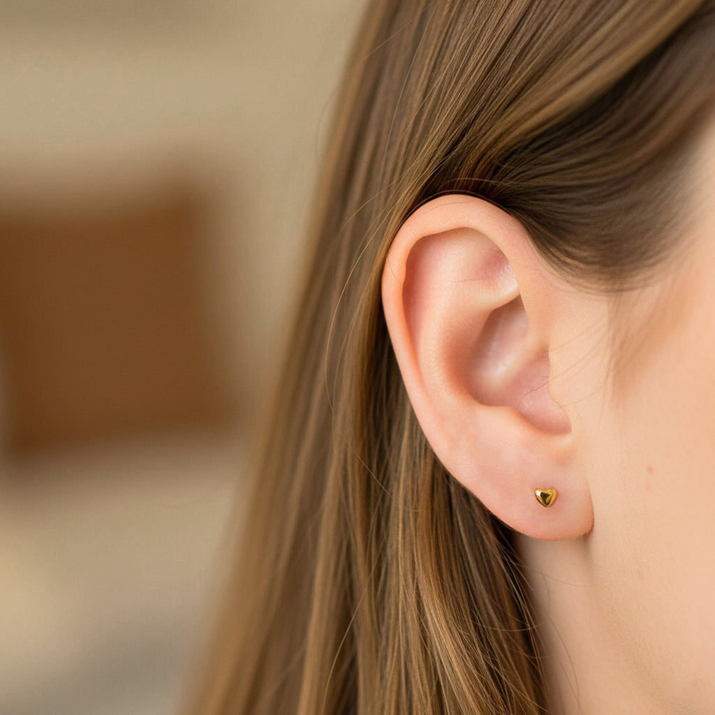 Oreja de modelo usando un topito en forma de corazón en oro amarillo de 18 quilates de Joyería Caracas. 