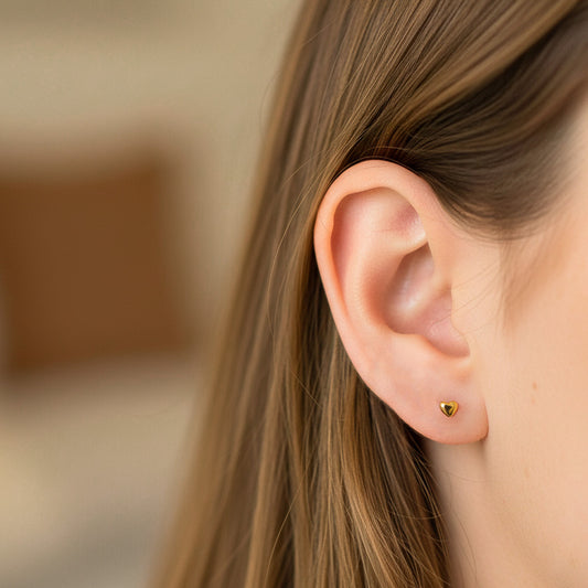 Oreja de modelo usando un topito en forma de corazón en oro amarillo de 18 quilates de Joyería Caracas. 
