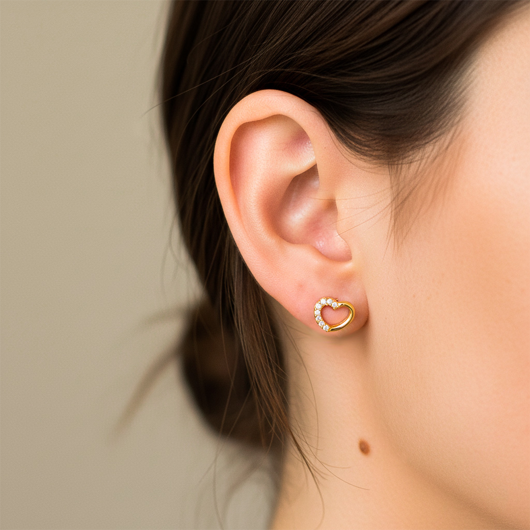 Oreja de modelo usando un topito en forma de corazón en oro amarillo de 18 quilates con cristales de color blanco de Joyería Caracas. 