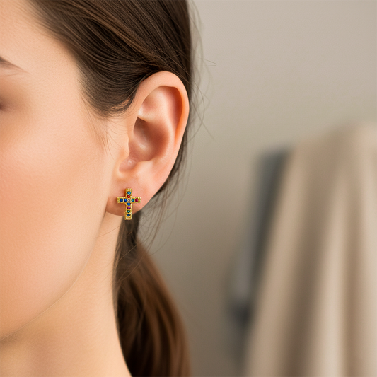 Oreja de modelo usando un topito en forma de cruz en oro amarillo de 18 quilates con cristales de distintos colores de Joyería Caracas. 