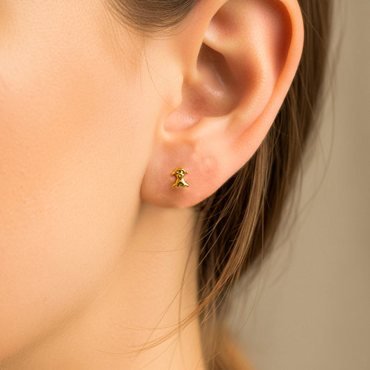 Oreja de modelo usando un topito en forma de perrito en oro amarillo de 18 quilates de Joyería Caracas.