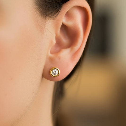 Oreja de modelo usando un topito en forma de dona en oro amarillo de 18 quilates con cristal de color blanco en el centro de Joyería Caracas. 