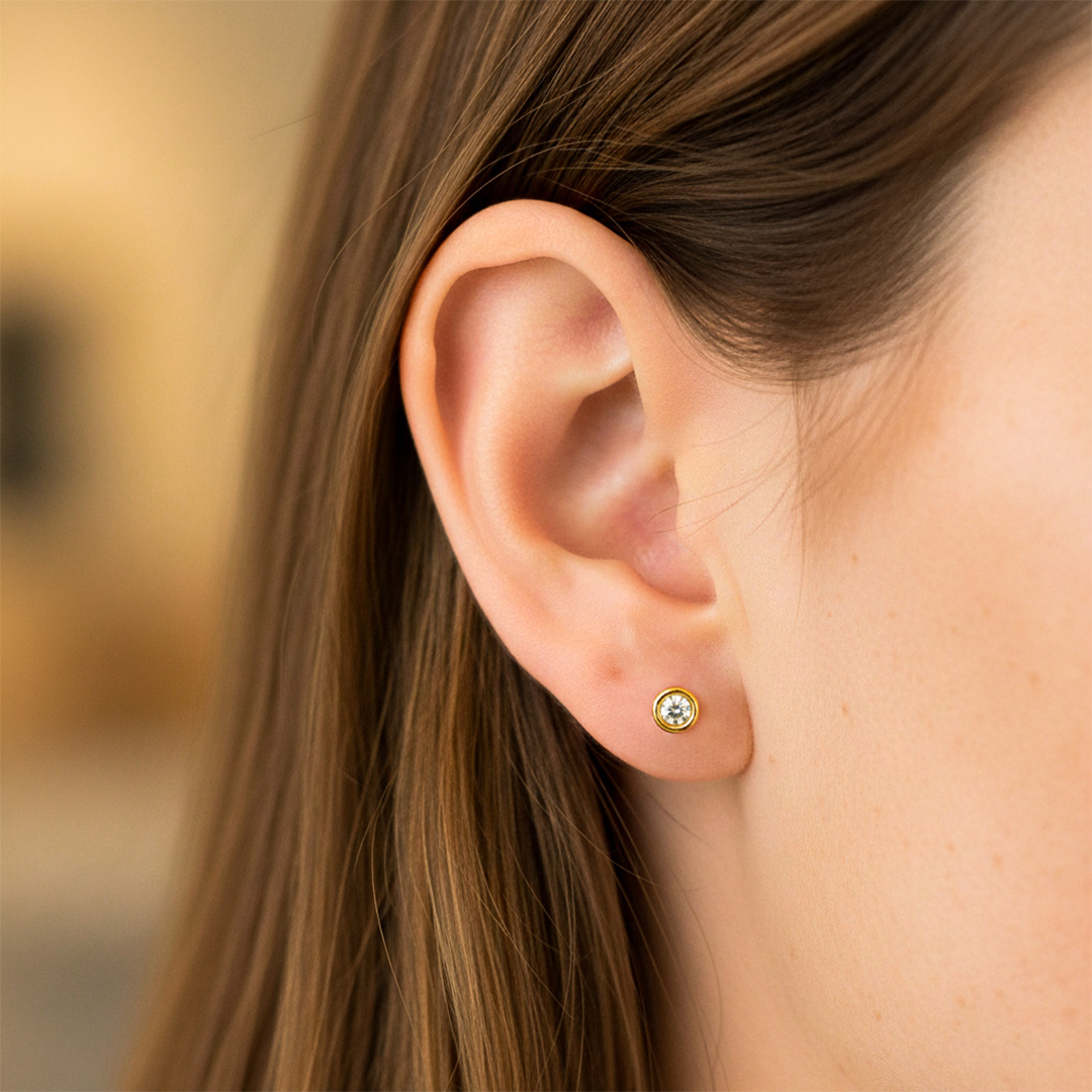 Oreja de modelo usando un topito biselado en oro amarillo de 18 quilates con cristal de color blanco de Joyería Caracas. 