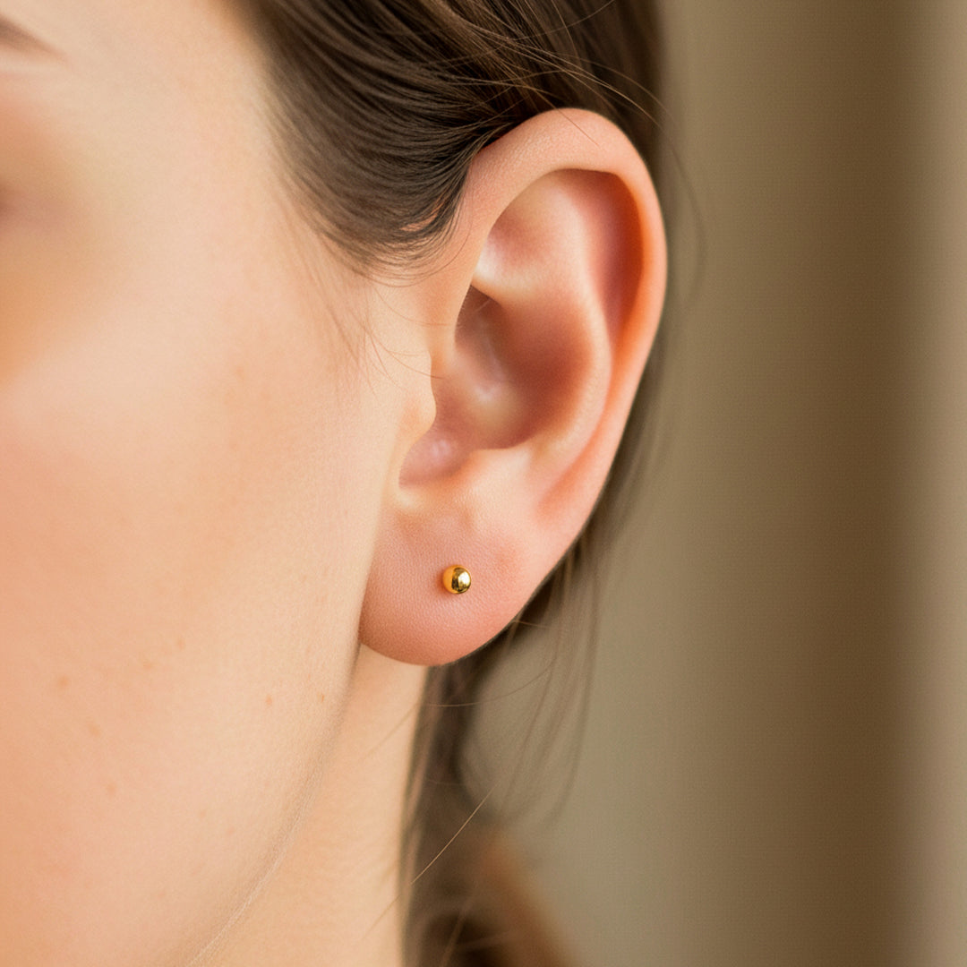 Oreja de modelo usando un topito de esfera lisa en oro amarillo de 18 quilates de Joyería Caracas. 