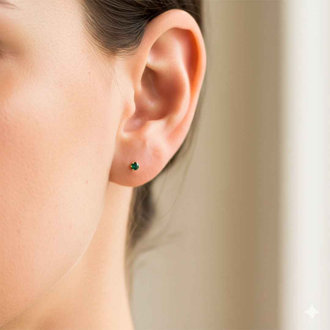 Oreja de modelo usando un topito en oro amarillo de 18 quilates con Esmeralda de 2,25mm de Joyería Caracas.