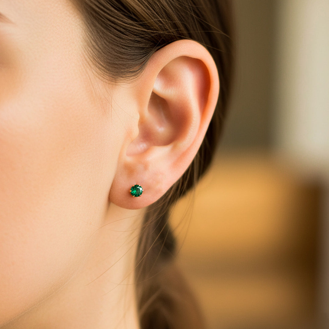 Oreja de modelo usando un topito en oro amarillo de 18 quilates con Esmeralda de Joyería Caracas. 