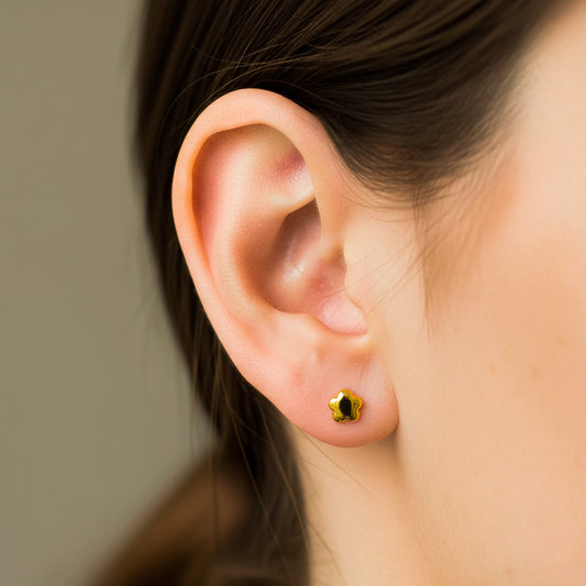 Oreja de modelo usando un topito en forma de estrella lisa en oro amarillo de 18 quilates de Joyería Caracas.