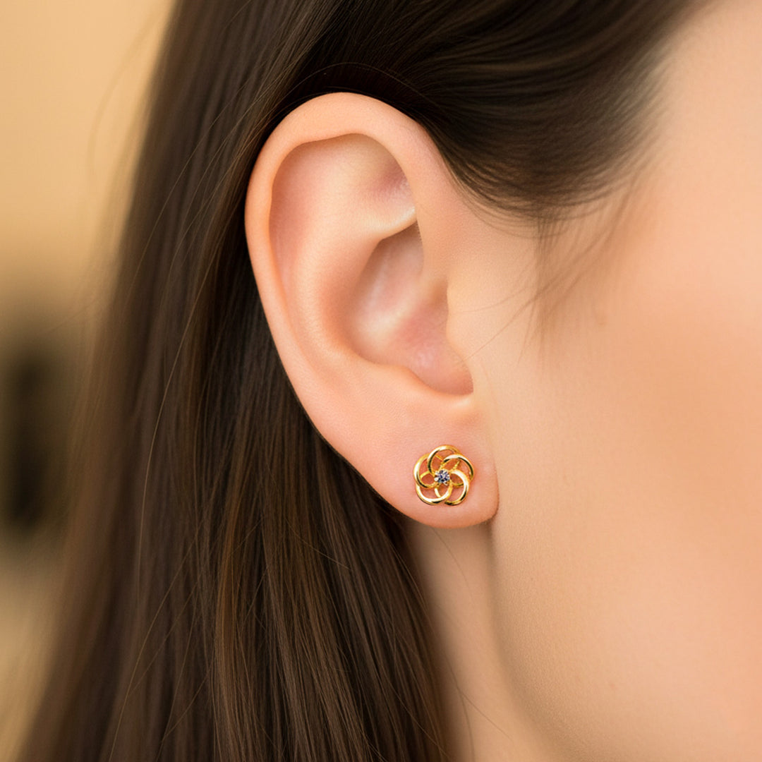 Oreja de modelo usando un topito en forma de flor espiral en oro amarillo de 18 quilates de Joyería Caracas. 