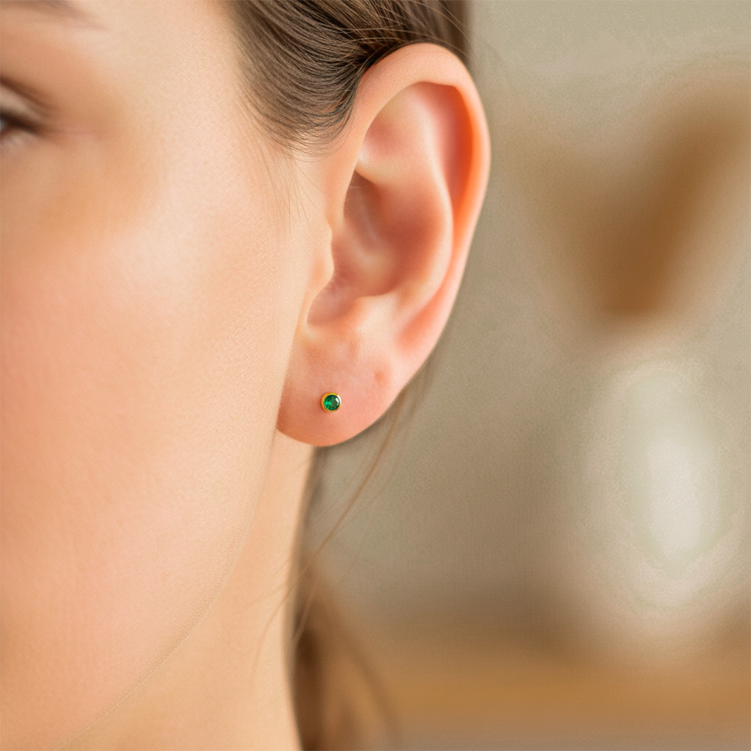 Oreja de modelo usando un topito redondo en oro amarillo de 18 quilates con Esmeralda de Joyería Caracas. 