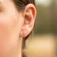 Oreja de modelo usando un topito de fila cristales en oro amarillo de 18 quilates con cristales de color blanco de Joyería Caracas. 