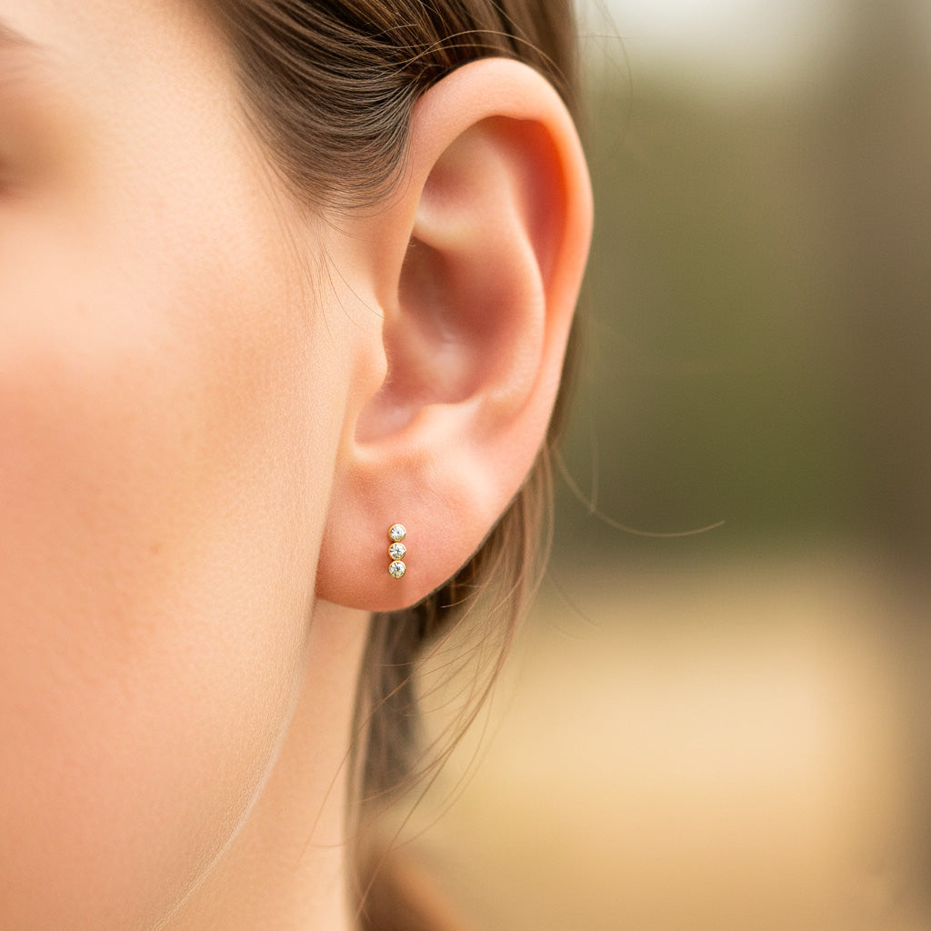 Oreja de modelo usando un topito de fila cristales en oro amarillo de 18 quilates con cristales de color blanco de Joyería Caracas. 
