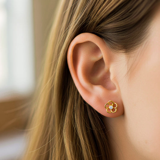 Oreja de modelo usando un topito en forma de flor de 5 pétalos en oro amarillo de 18 quilates con cristal de color blanco en el centro de Joyería Caracas. 