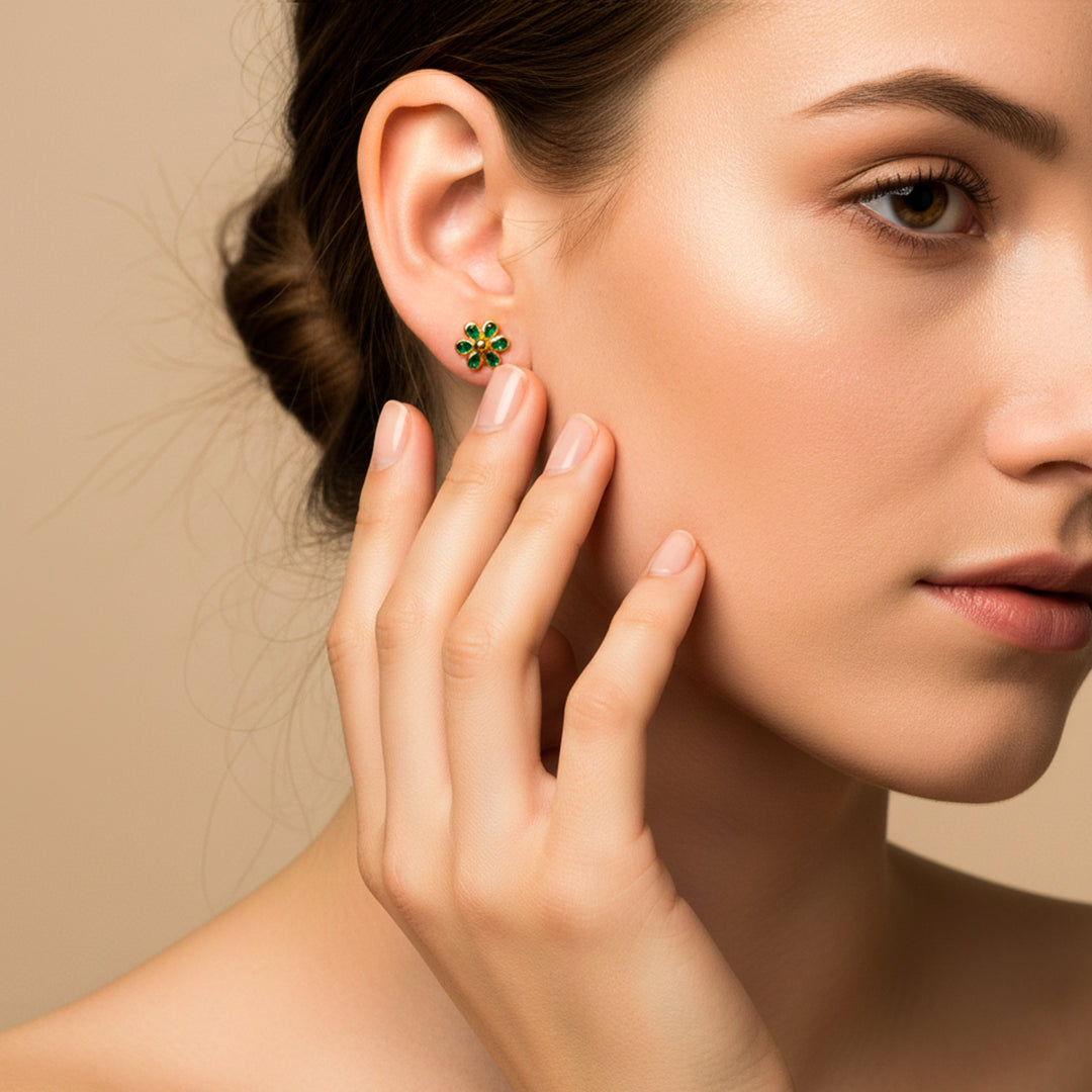 Oreja de modelo usando un topito en forma de flor en oro amarillo de 18 quilates con cristales de color verde de Joyería Caracas.