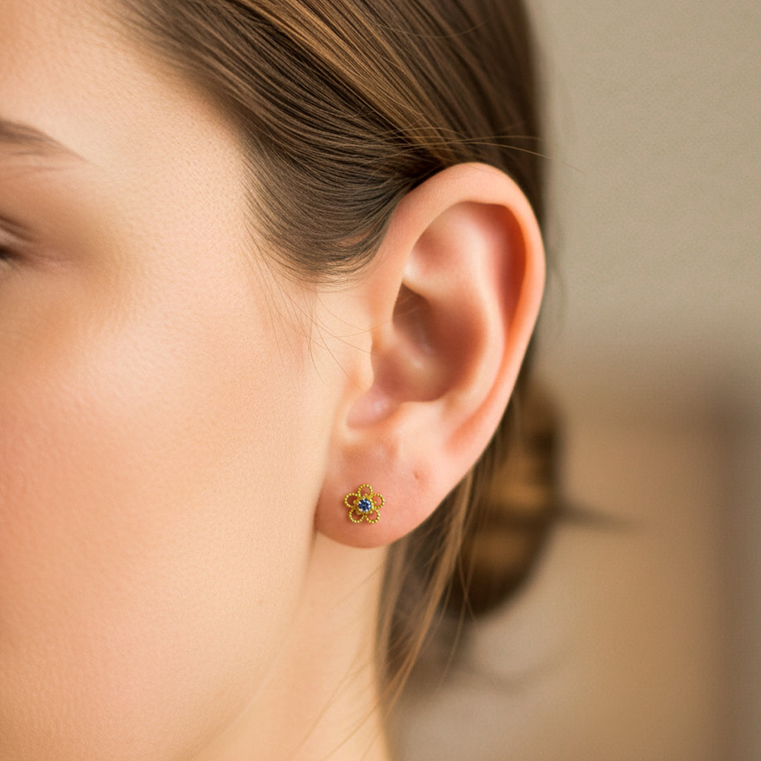 Oreja de modelo usando un topito en forma de flor de lazo en oro amarillo de 18 quilates con cristal de Joyería Caracas. 