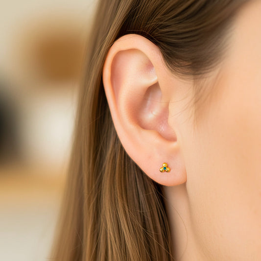 Oreja de modelo usando un topito en forma de flor acanalada en oro amarillo de 18 quilates de Joyería Caracas. 