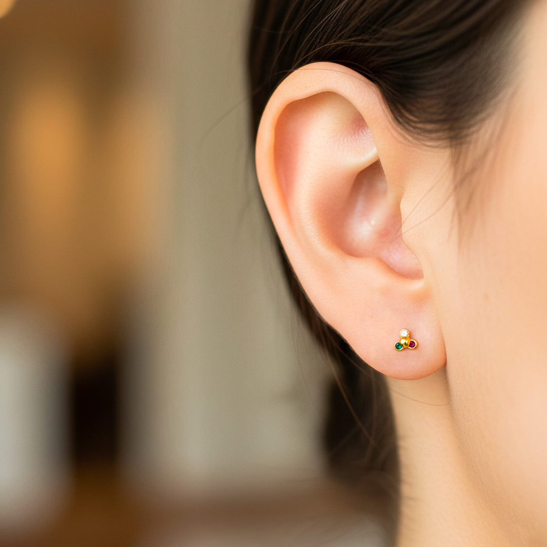 Oreja de modelo usando un topito en forma de flor de loto en oro amarillo con cristales de Joyería Caracas. 