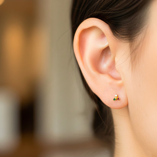 Oreja de modelo usando un topito en forma de flor de loto en oro amarillo con cristales de Joyería Caracas. 