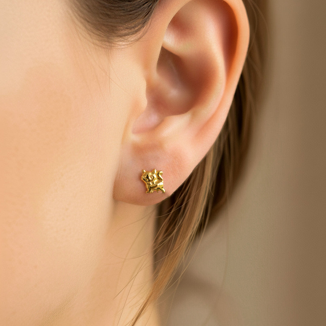 Oreja de modelo usando un topito en forma de gatico en oro amarillo de 18 quilates de Joyería Caracas. 