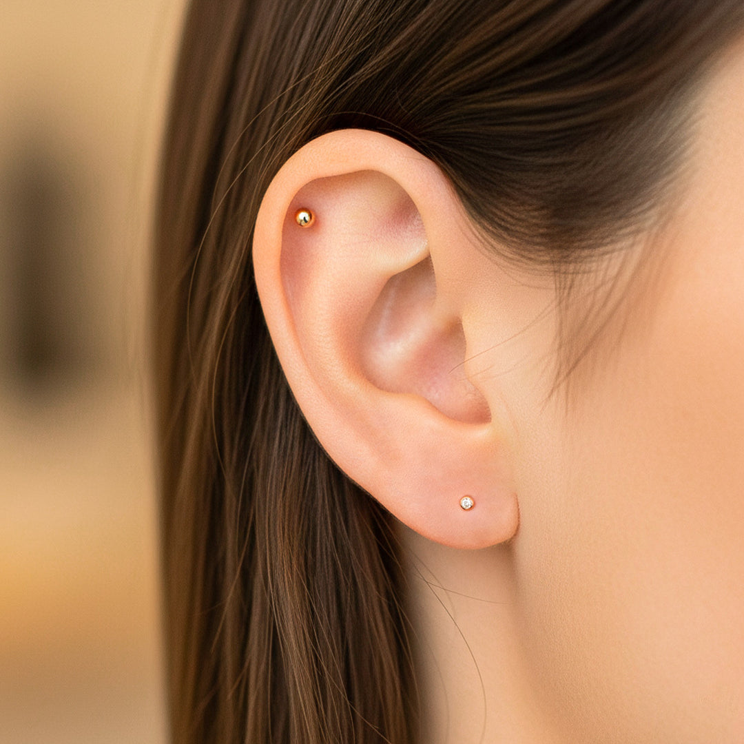 Oreja de modelo usando un topito redondo en oro rosa de 18 quilates con cristal de Joyería Caracas. 