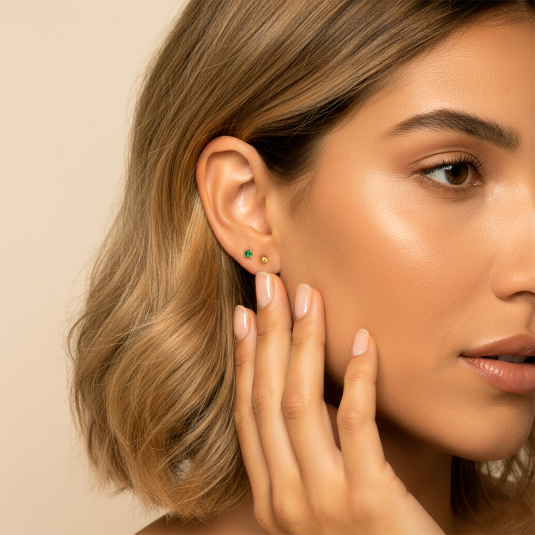 Oreja de modelo usando un topito en oro amarillo de 18 quilates con Esmeralda redonda de 2,5mm de Joyería Caracas.