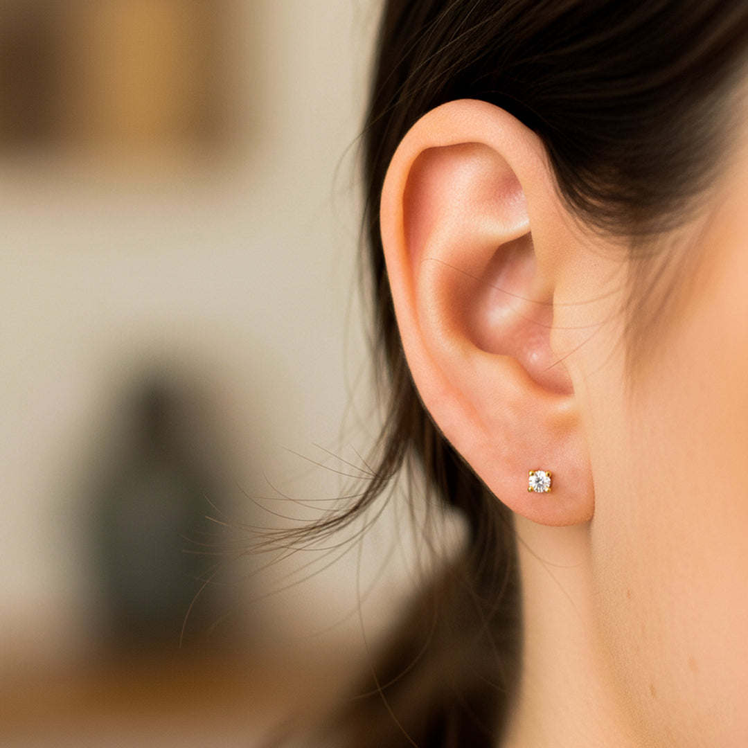 Oreja de modelo usando un topito en oro amarillo de 18 quilates con cristal de color blanco de Joyería Caracas. 