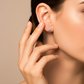 Oreja de modelo usando un topito en oro amarillo de 18 quilates con cristal de color blanco de Joyería Caracas. 
