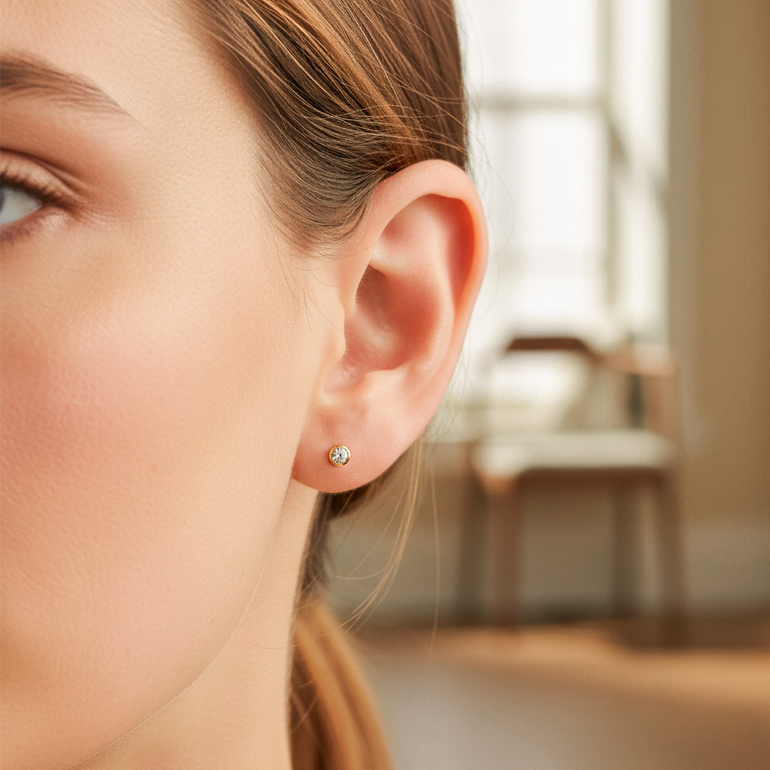 Oreja de modelo usando un topito redondo biselado en oro amarillo de 18 quilates con cristal de Joyería Caracas. 