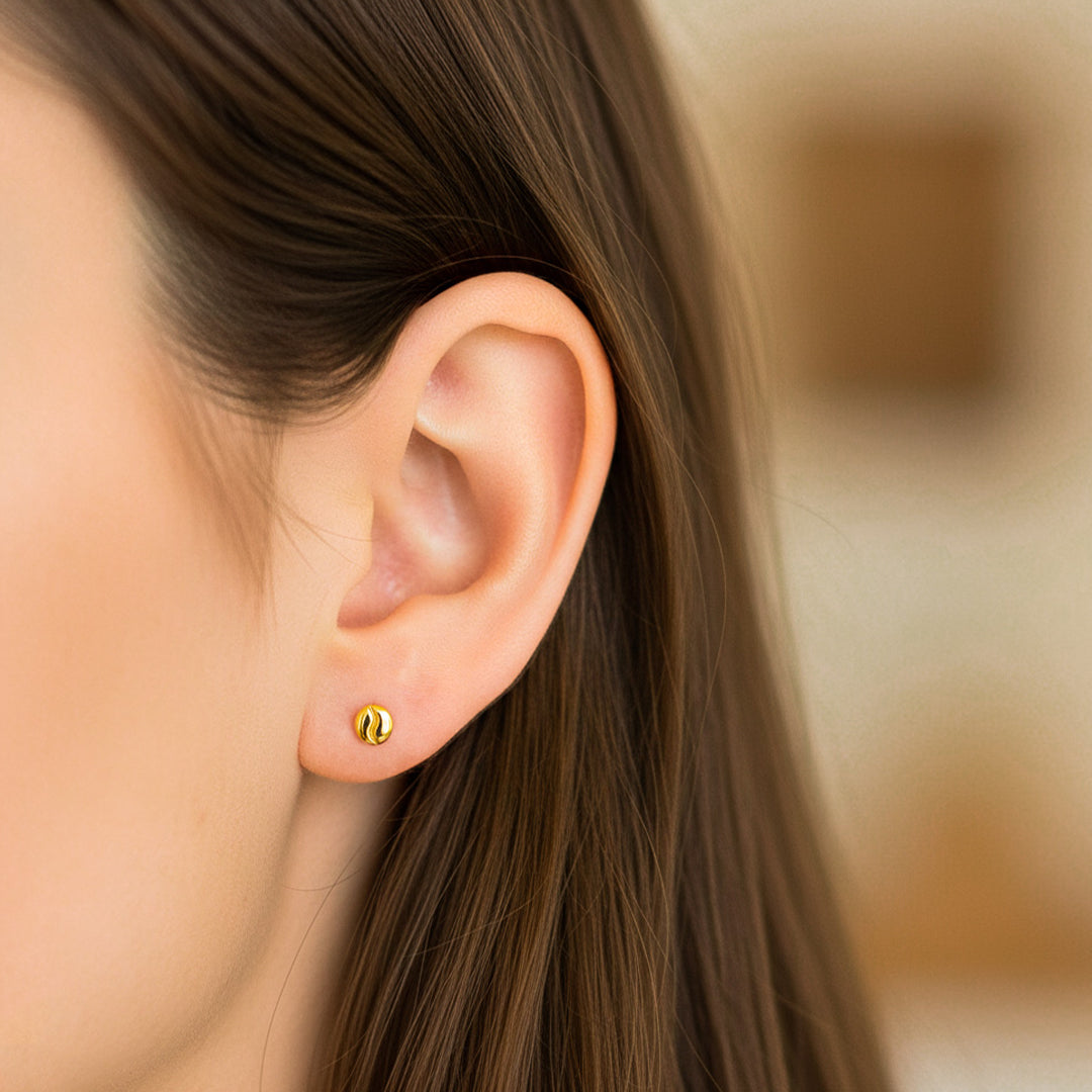 Oreja de modelo usando un topito en forma de grano de café en oro amarillo de 18 quilates de Joyería Caracas. 